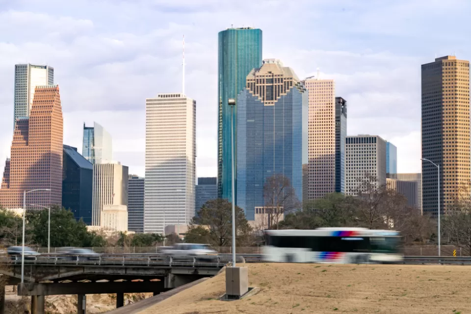 View of Houston freeway with bus, cars, and downtown skyline in background
